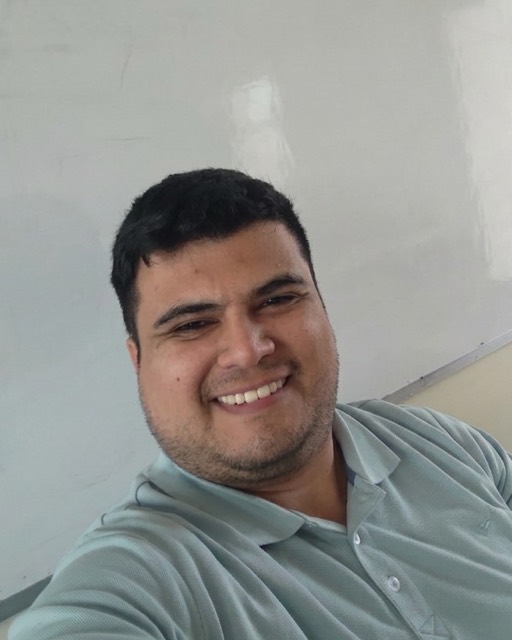 Niro Espina sonriendo en su sala de clases, frente a la pizarra